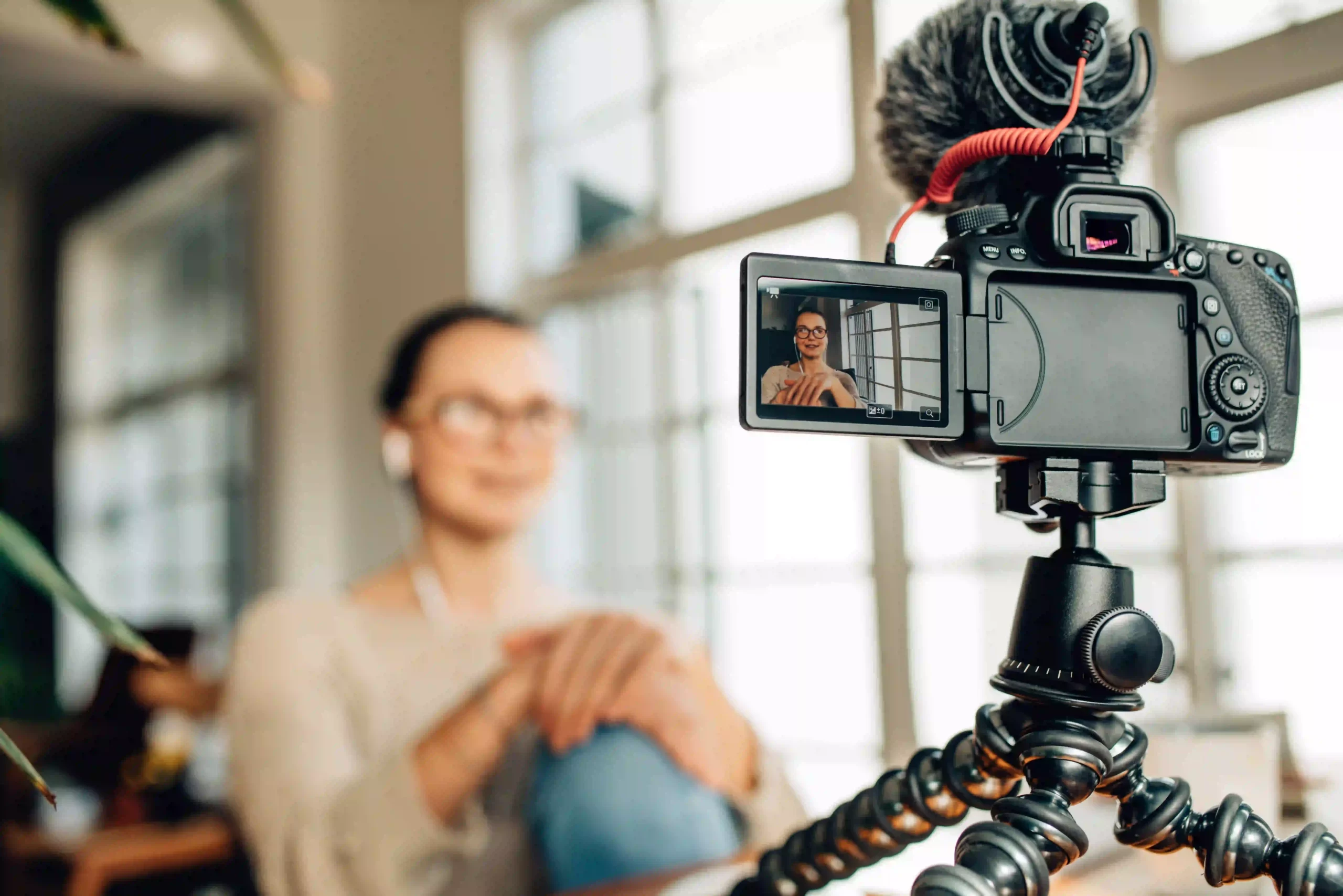 Woman blogger recording her content on a DSLR camera placed on a tripod.