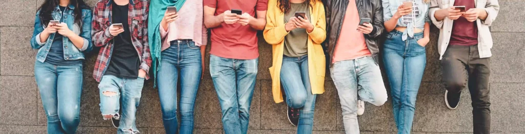 Millennial people addicted to new technology, using their smartphones outdoor. Concept of tech, social media, generation z and youth lifestyle.