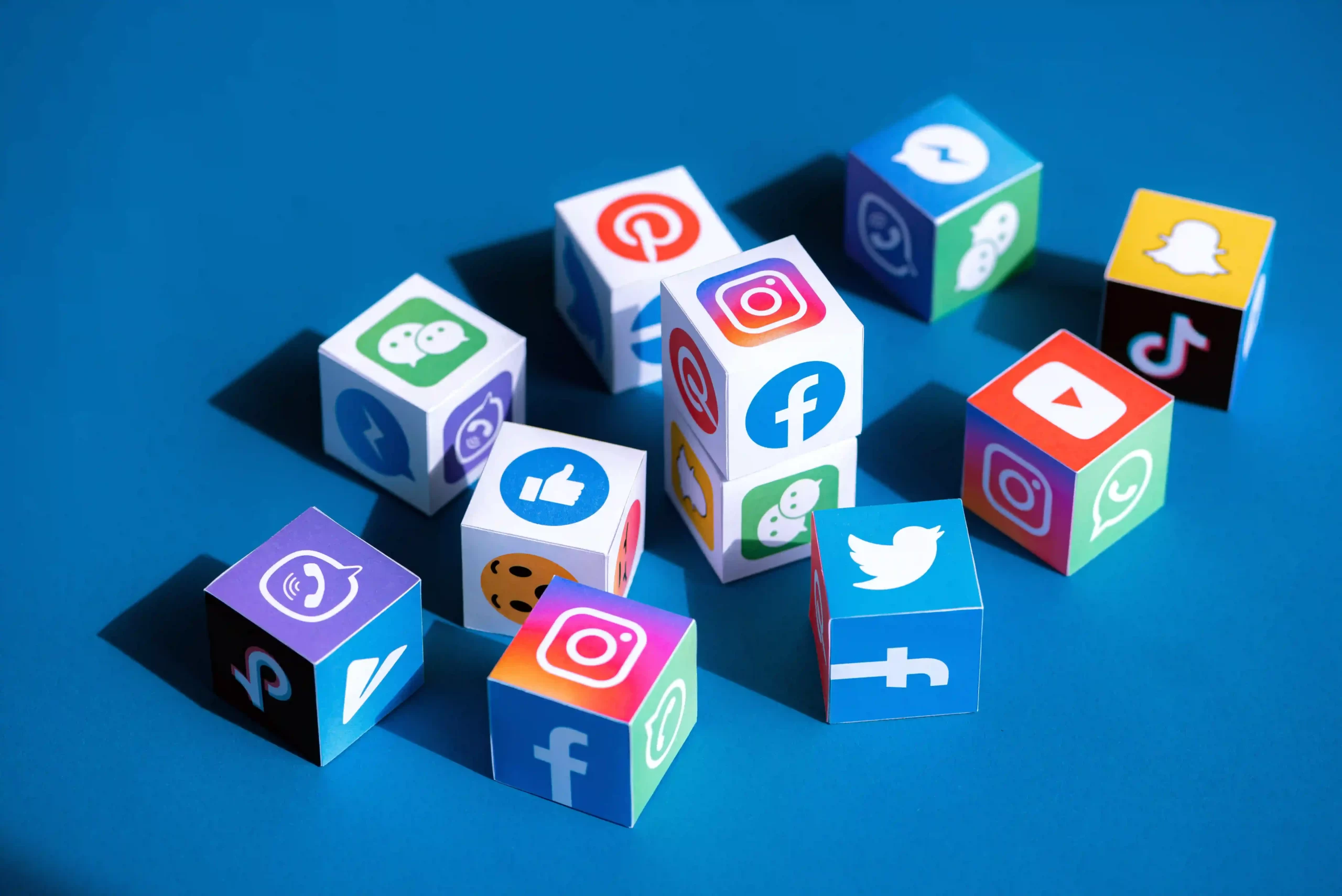 Social media apps logotypes printed on cubes, blue background.
