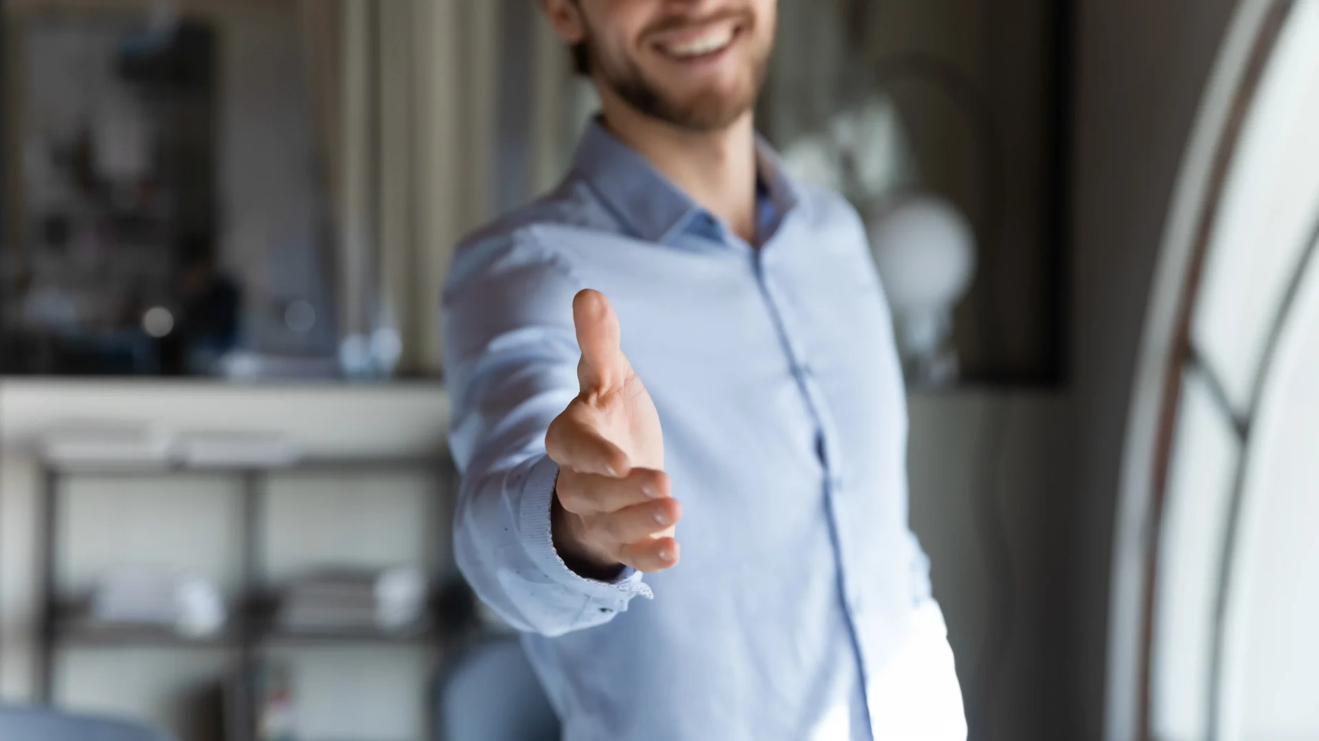 Male person extends hand in welcoming gesture.