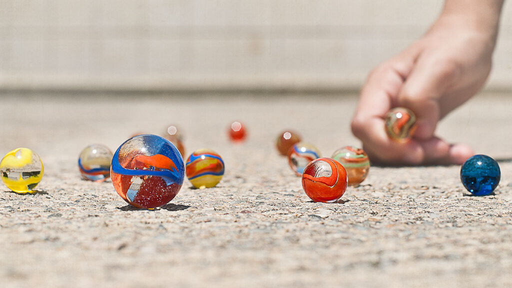 Genom inbound marketing gör du dig själv trovärdig hos kunderna. På bilden syns en närbild av små glasbollar på marken och en mänsklig hand som kastar en annan glasboll.