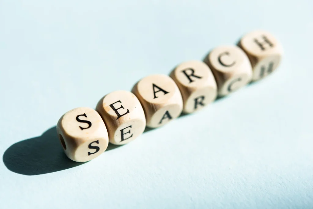 Close-up of wooden cubes arranged in a row to spell the word 'SEARCH' on a light background, symbolizing online search and keyword research in SEO.