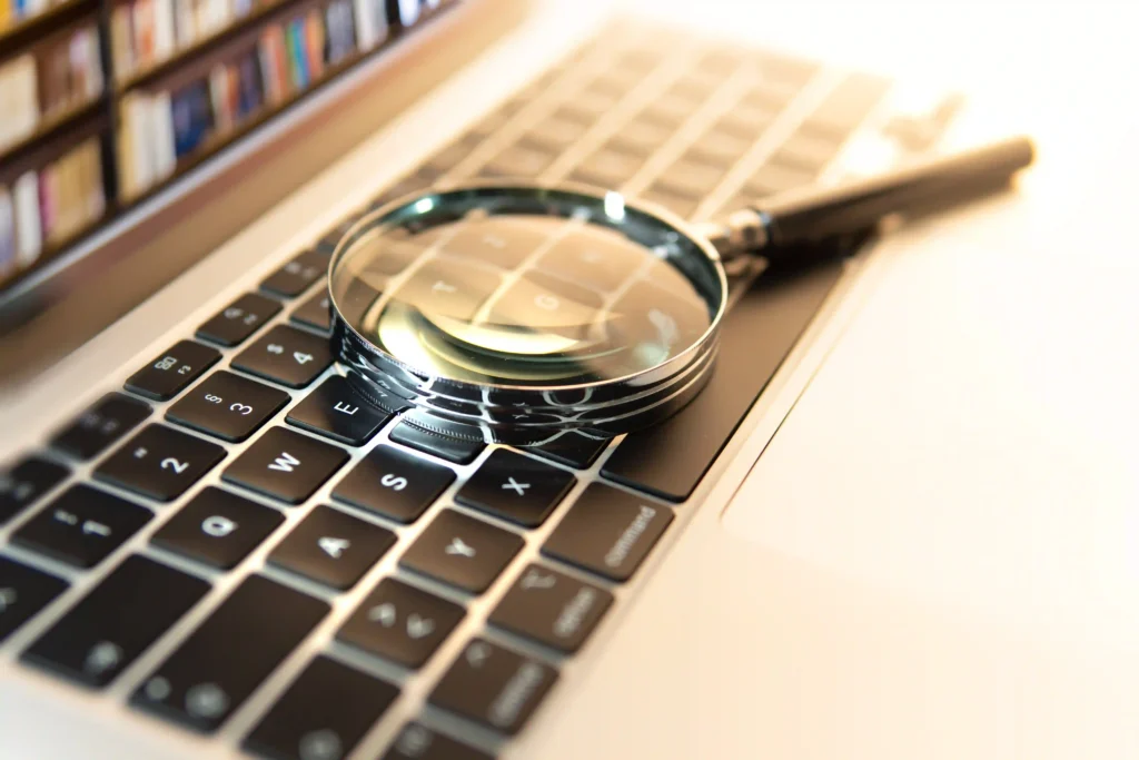 Magnifying glass placed on a laptop keyboard, symbolizing keyword research and online search, in the context of SEO.