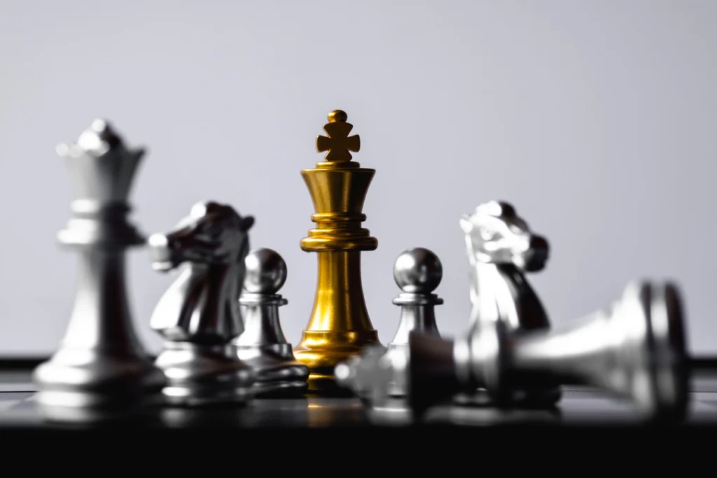 A golden chess king stands tall among silver chess pieces, symbolizing strategy.