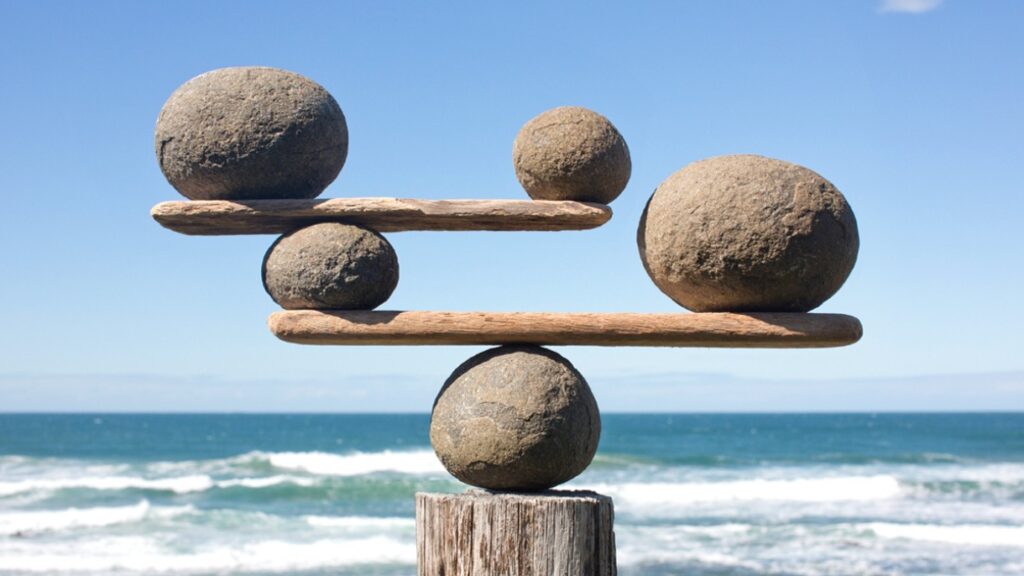 Stacked stones balanced on wooden planks, symbolizing the need for moderation and equilibrium when using keywords to keep content clear, readable, and user-friendly.
