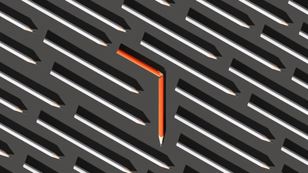 Single orange pencil facing a different direction among identical pencils, symbolizing misrouted traffic caused by incorrect DNS configuration.