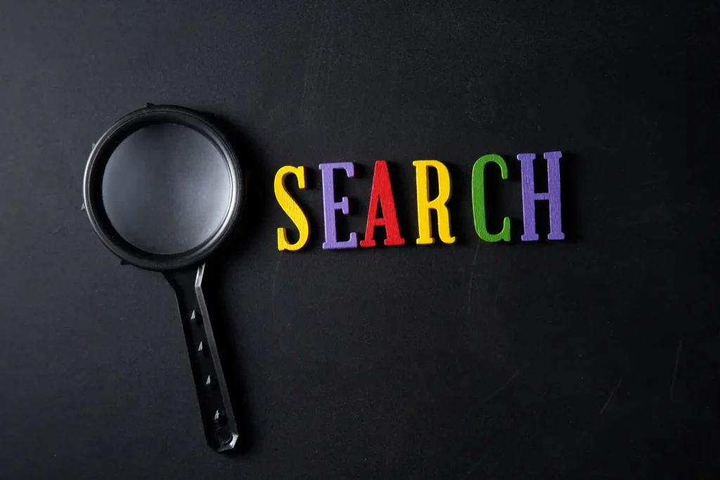 Magnifying glass next to colorful letters spelling “SEARCH” on a dark background, symbolizing search visibility and discoverability.